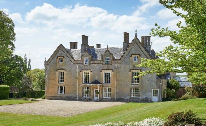 A large country estate surrounded by dramatic green fields