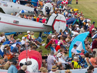 At AirVenture in Oshkosh, Wisconsin, airplane fans have found a good spot by a brace of twin-tailed classic aircraft to watch the airshow.