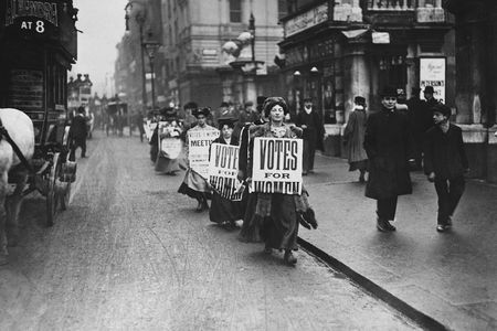 Suffragettes protest along a London street wearing sandwich boards in 1912.