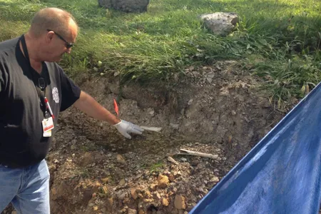 Schuylkill County Deputy Coroner Joe Pothering points to human bones in embankment along Route 61 in Schuylkill Haven, Pennsylvania August 14, 2015. Forensic archaeologists on Friday began excavating a highway embankment in eastern Pennsylvania, looking for more bones believed to be from impoverished victims of the worldwide Spanish flu pandemic in 1918.