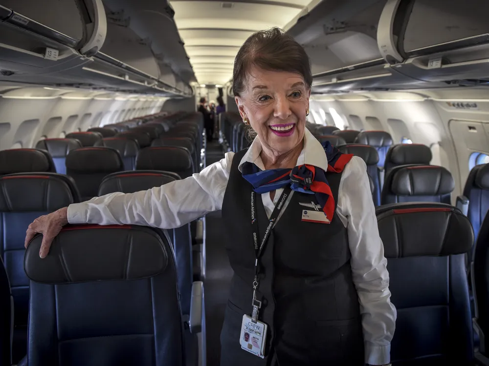 Woman in flight attendant uniform on a plane smiling