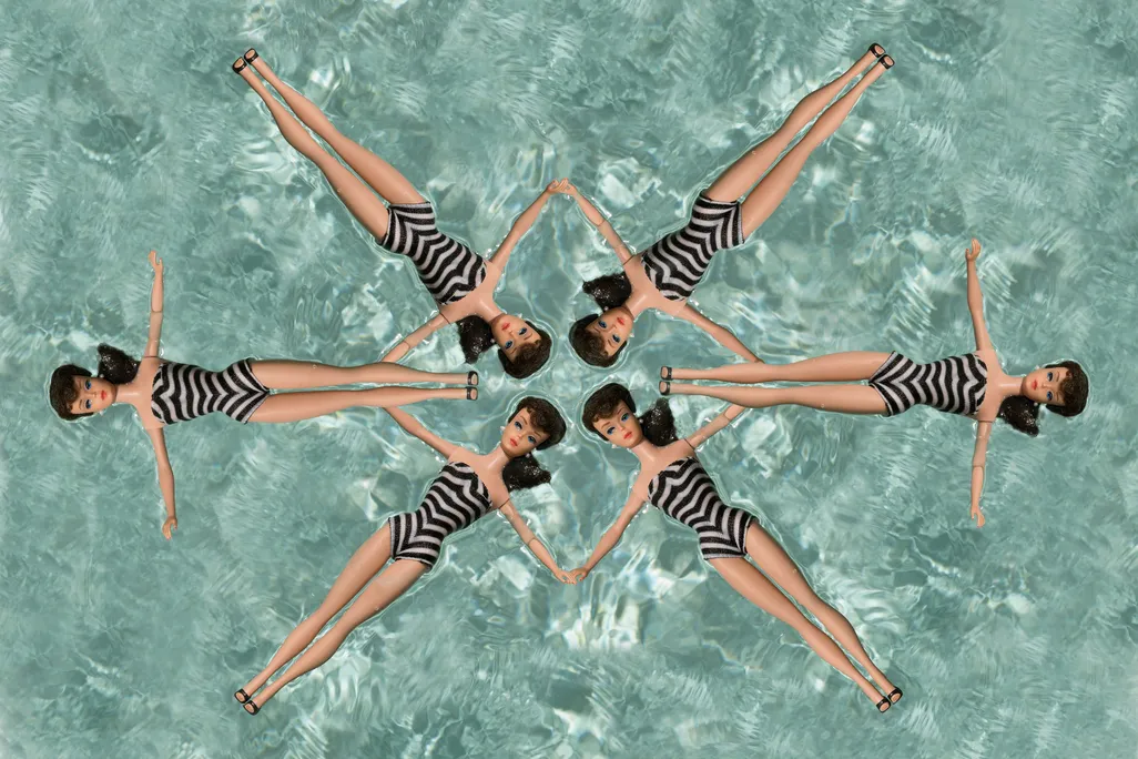 six Barbie dolls wearing zebra striped swimsuits in a synchronized formation in a swimming pool