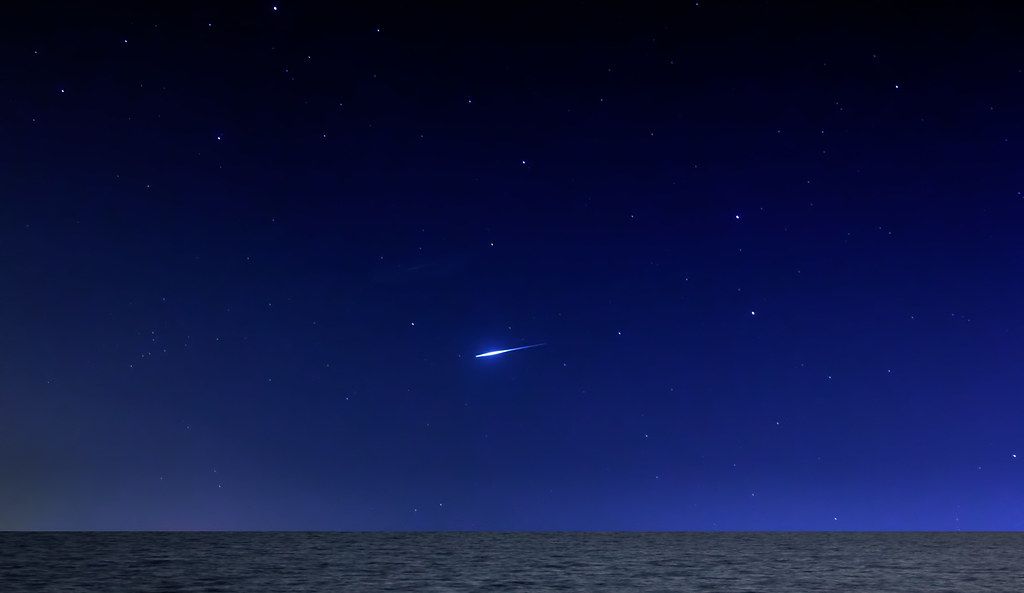 Meteor streaking across dark sky with stars