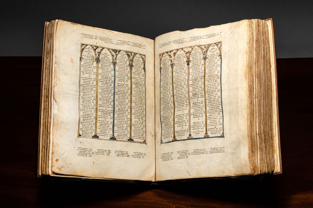 Book with Hebrew writing open on a stand against a dark backdrop