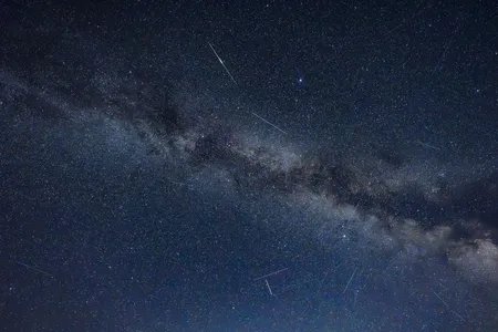 A long-exposure view of the Milky Way, seen from Brandenburg, Germany, is cut through by the light trails of passing satellites.