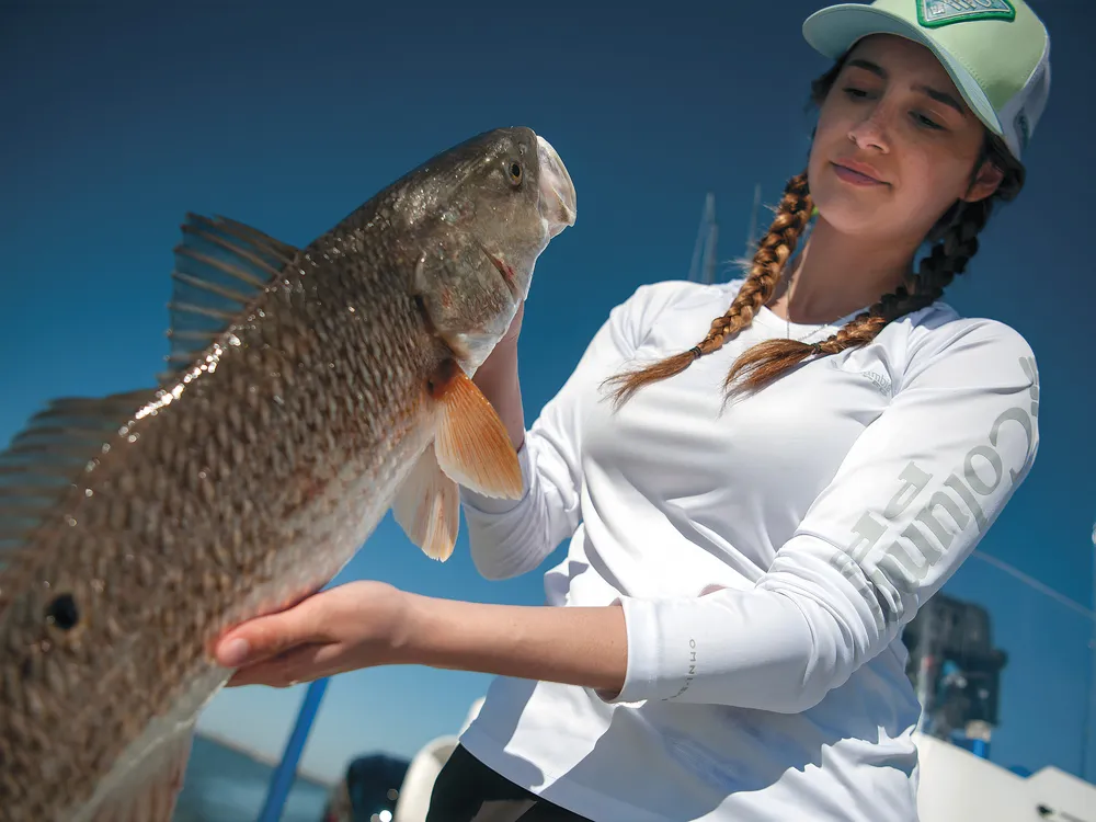 a women holds a freshly caught fish