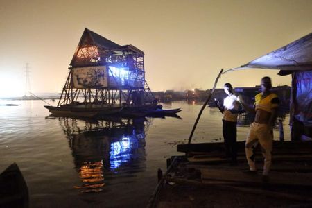 Residents of Makoko look on its floating school at night in December. Today, the school is nothing more than an empty, broken platform. 