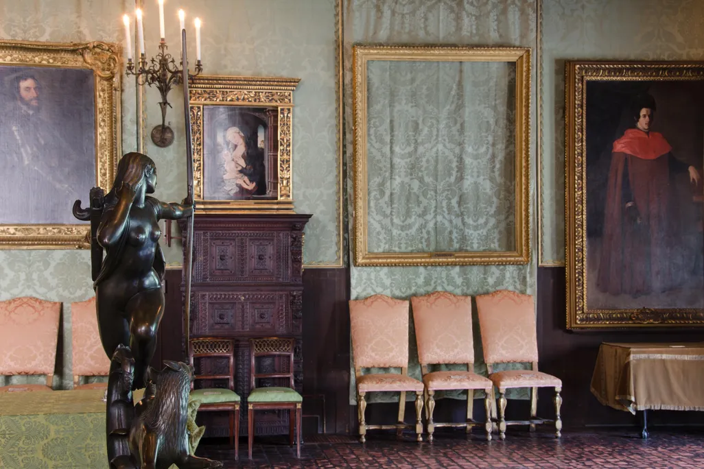 Empty gilded frames loom over chairs at the museum