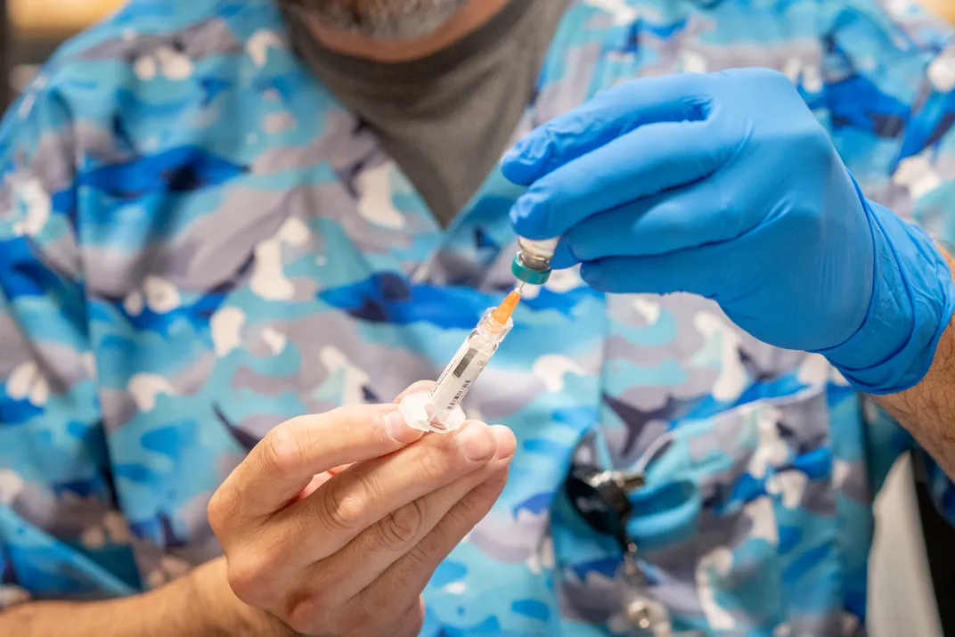 a person fills a syringe with a gloved hand