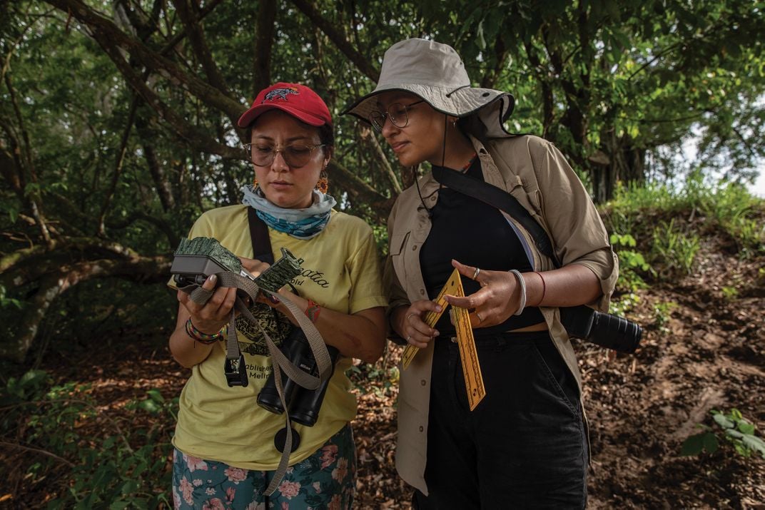 Katerín Corrales, left, and Sofía Fernández Africano, both biologists, examine photographs from camera traps set along the Magdalena to track the growth and distribution of the hippo population and analyze targets for sterilization;