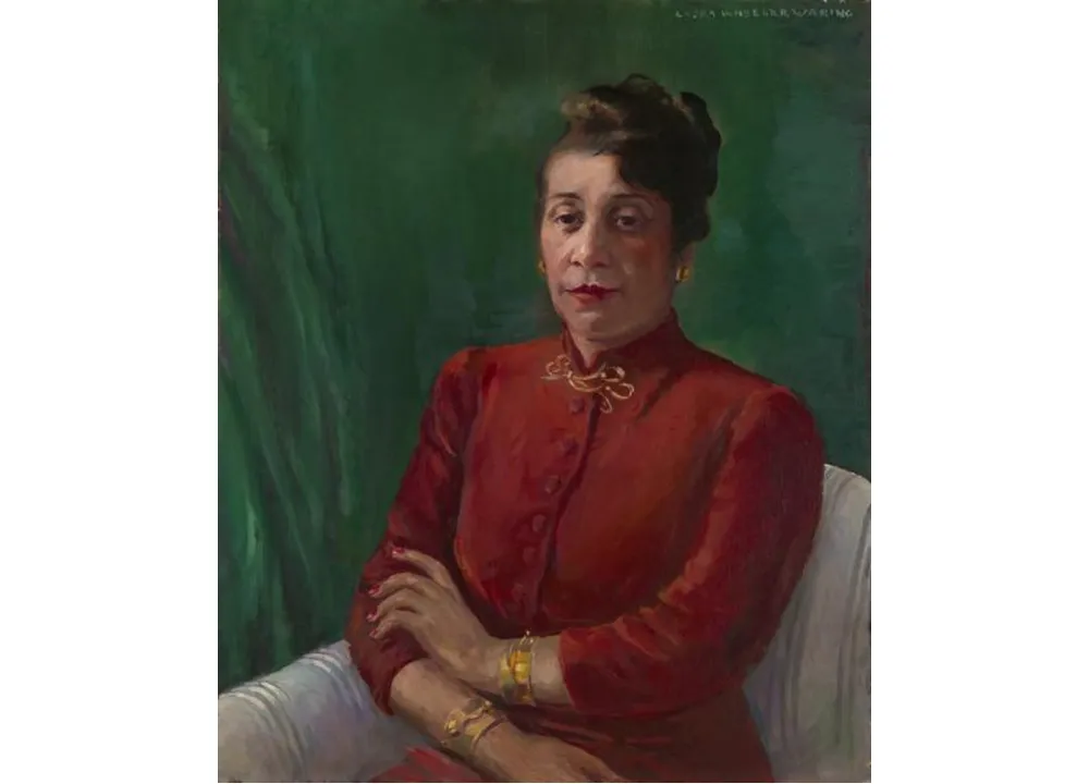 Distinguished in a high-collared, red shirt and gold jewelry, Alma Thomas wears her hair up and looks directly at the viewer. Her arms are crossed loosely, and she sits before a green background.