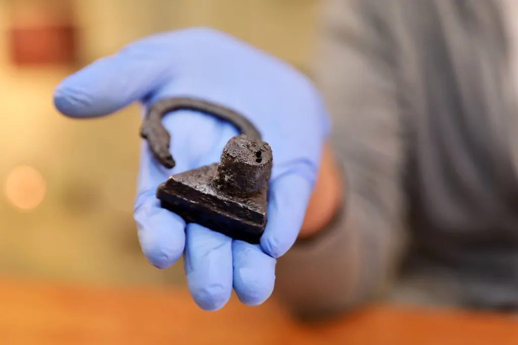 An archaeologist examines the triangular padlock found around the Polish woman's left big toe.