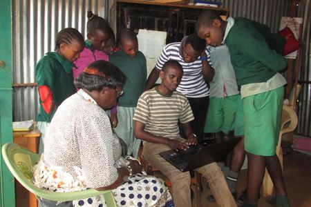 Zacharia Muinde of Map Kibera Trust shows teachers and students their school's page on Open Schools Kenya, a mapping project that helps residents find information on local schools.