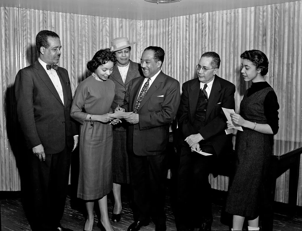 black and white photo of formally dressed black men and women with Langston Hughes