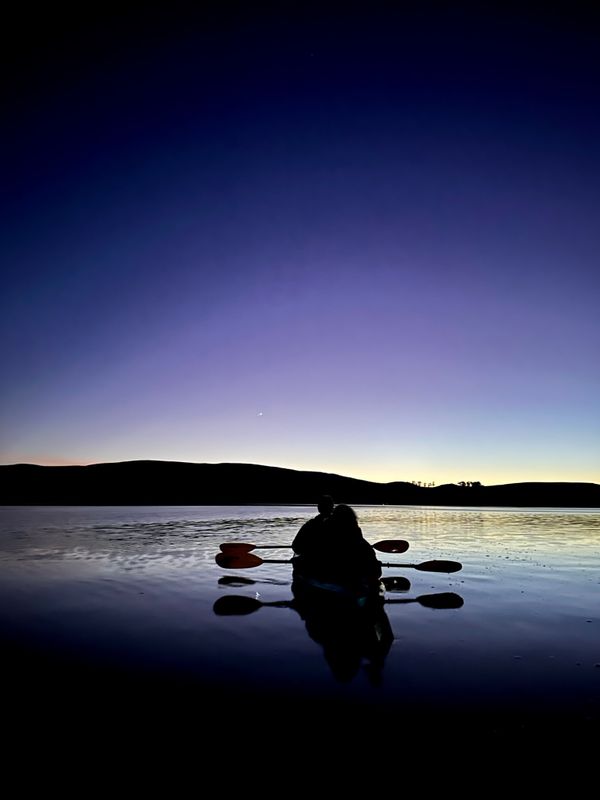 Kayakers paddle into the darkness at Tomales Bay. thumbnail