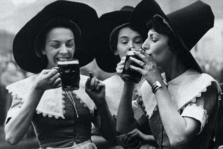 Three women dressed in period garb as alewives. The tall hats became a part of witch iconography.