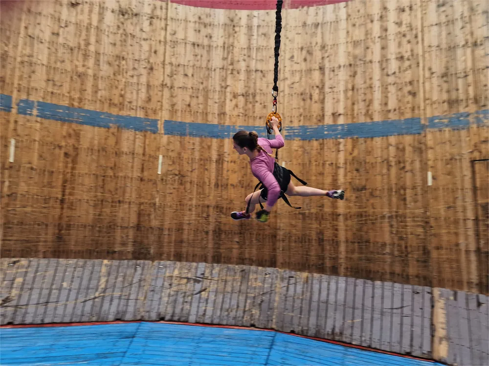 Woman tied to a bungee cord running around a cylindrical wall
