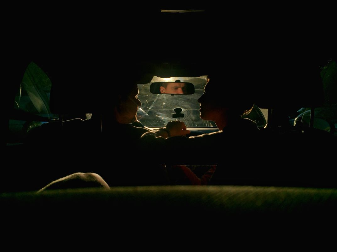 A family sits in a dramatically lit car