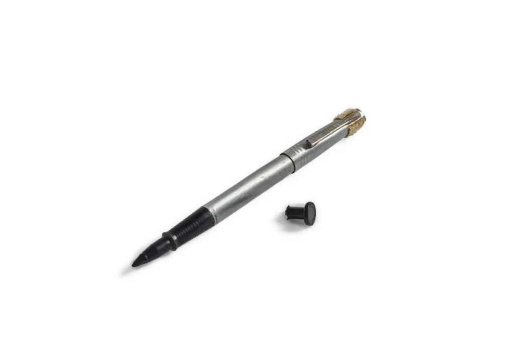 A pen and a little piece of black plastic against a white backdrop