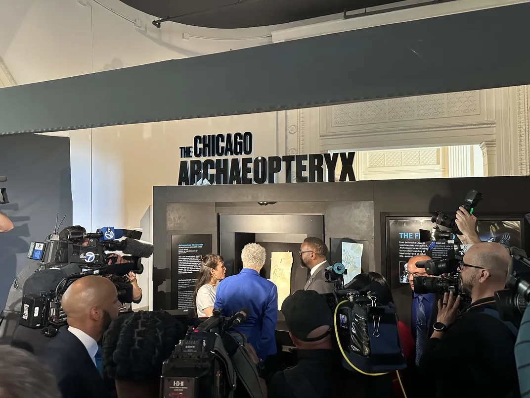 museum and political officials stand in front of the "chicago archaeopteryx" display, with members of the media standing in front