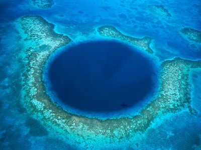 Belize's Lighthouse Reef Atoll surrounds the Blue Hole, a sunken cave system that is a haven for marine life and scuba divers.