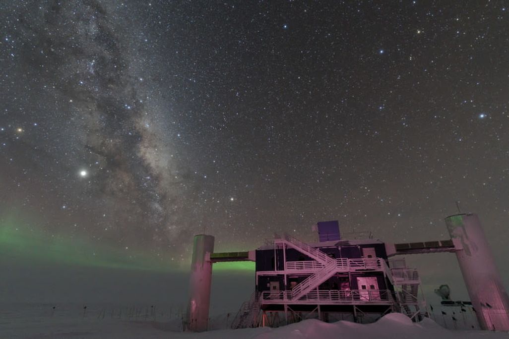 IceCube Lab with a starry night sky showing the Milky Way and faint green auroras