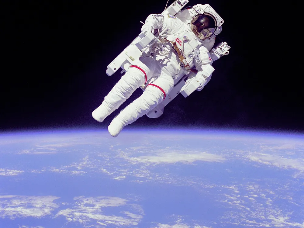 An image of Astronaut Bruce McCandless II participating in extra=vehicular activity in space. The astronaut appears to be floating out in space without being tethered to the space shuttle.