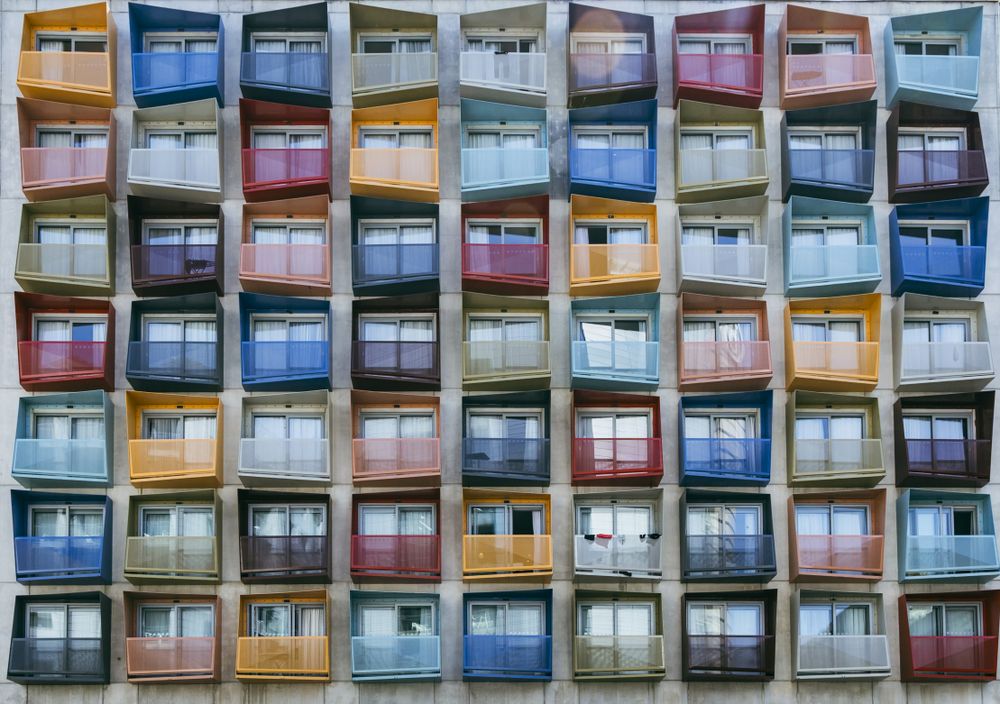 A residential building becomes a vibrant tapestry of repeating balconies in shifting colors. Each unit reflects a different story, yet together they form a striking urban kaleidoscope.