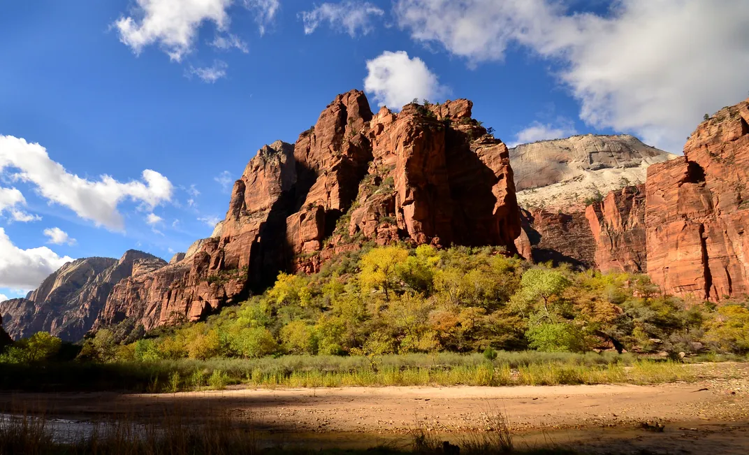 Red rock cliffs with green plants and blue sky