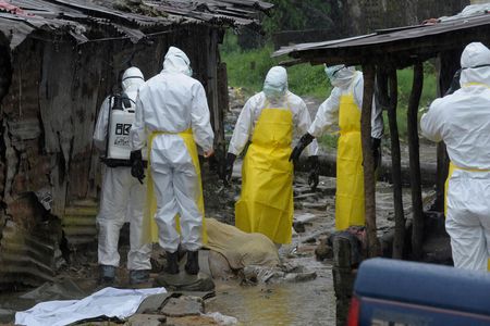 Health workers wearing protective clothing prepare to carry an abandoned dead body presenting with Ebola symptoms at Duwala market in Monrovia August 17, 2014.