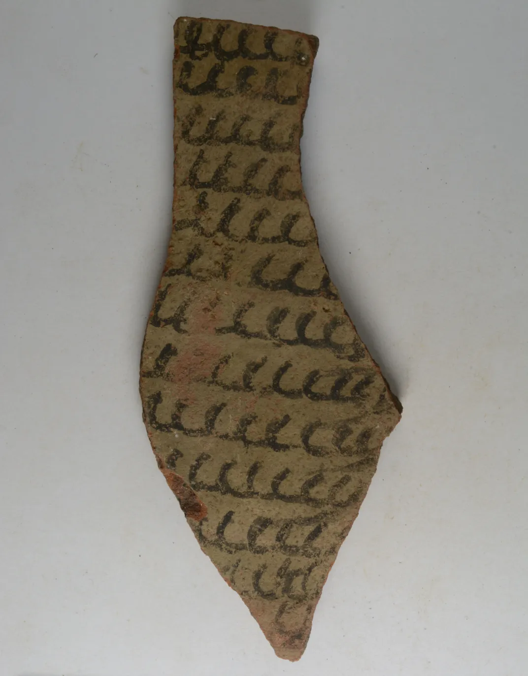 tie-shaped brown fragment with circular-like scribbles in black writing