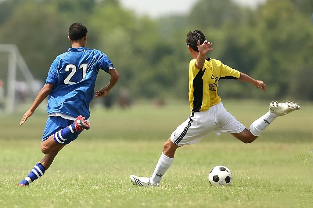 Two boys playing soccer on grass