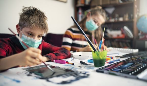 Image shows two children wearing masks painting