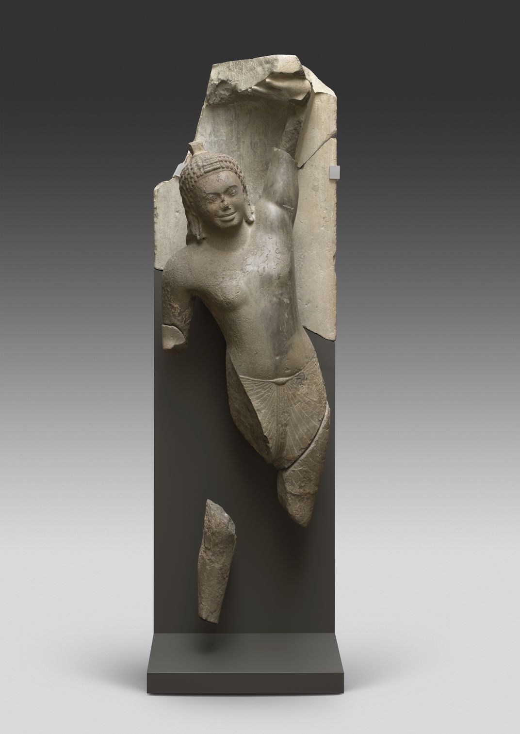 A reconstructed statue of a young boy, with left arm raised to the sky and lifting the base of mountain