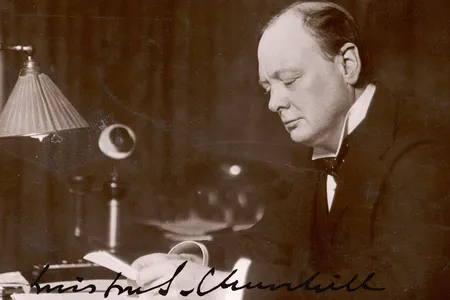 British statesman and author Winston Churchill reads correspondence at his desk in 1933.
