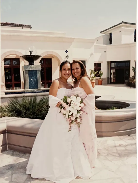 Quinceañera (fifteen-year-old girl) wearing a long strapless dress and posing by her mother's side.