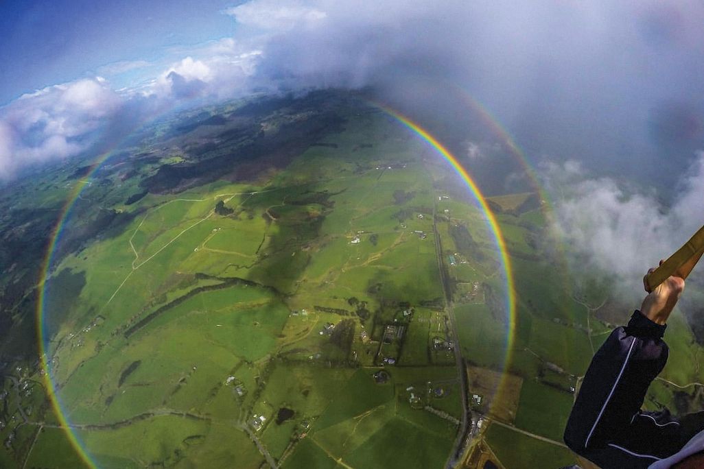 circular rainbow over green fields