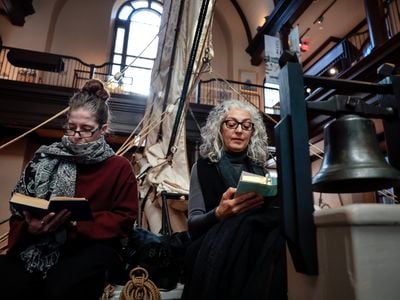 Two women follow along during the Moby Dick reading marathon at the&nbsp;New Bedford Whaling Museum.