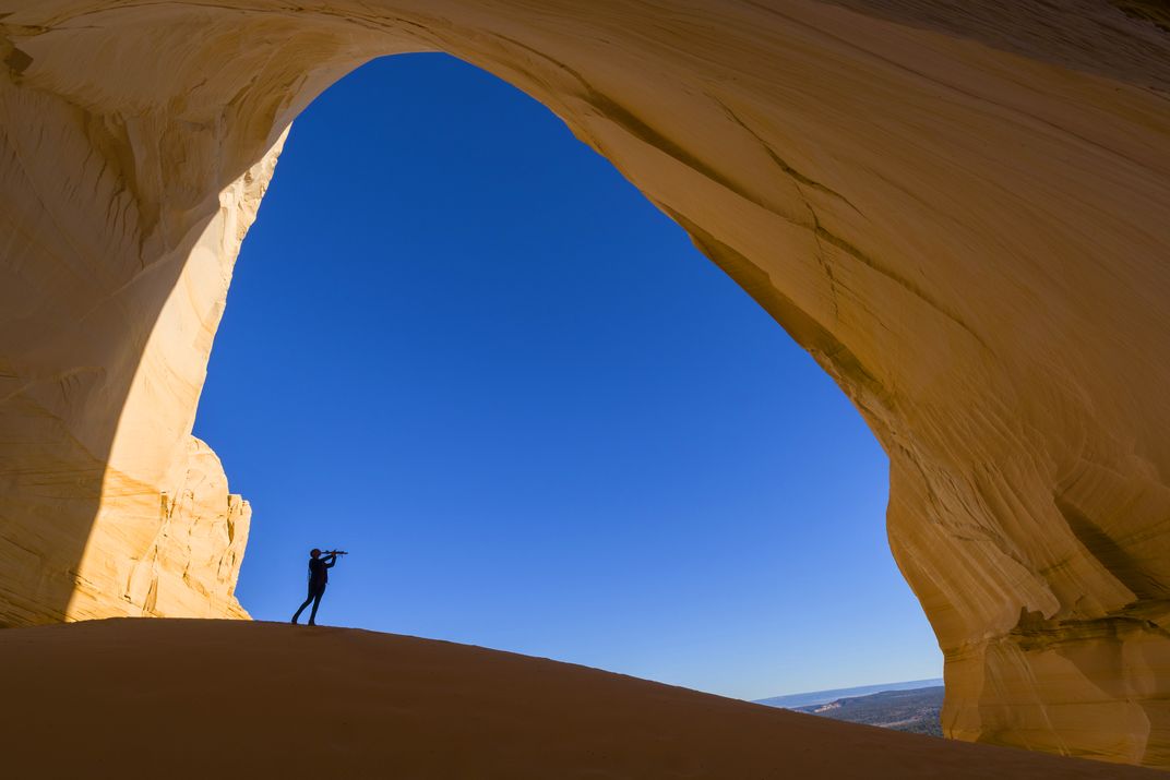 a person plays a flute in a natural rock arch