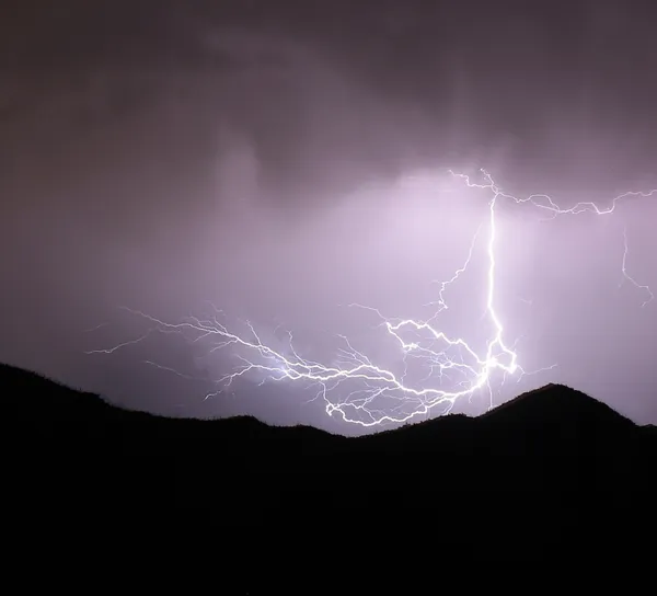 A lightning strike over a mountain hillside thumbnail