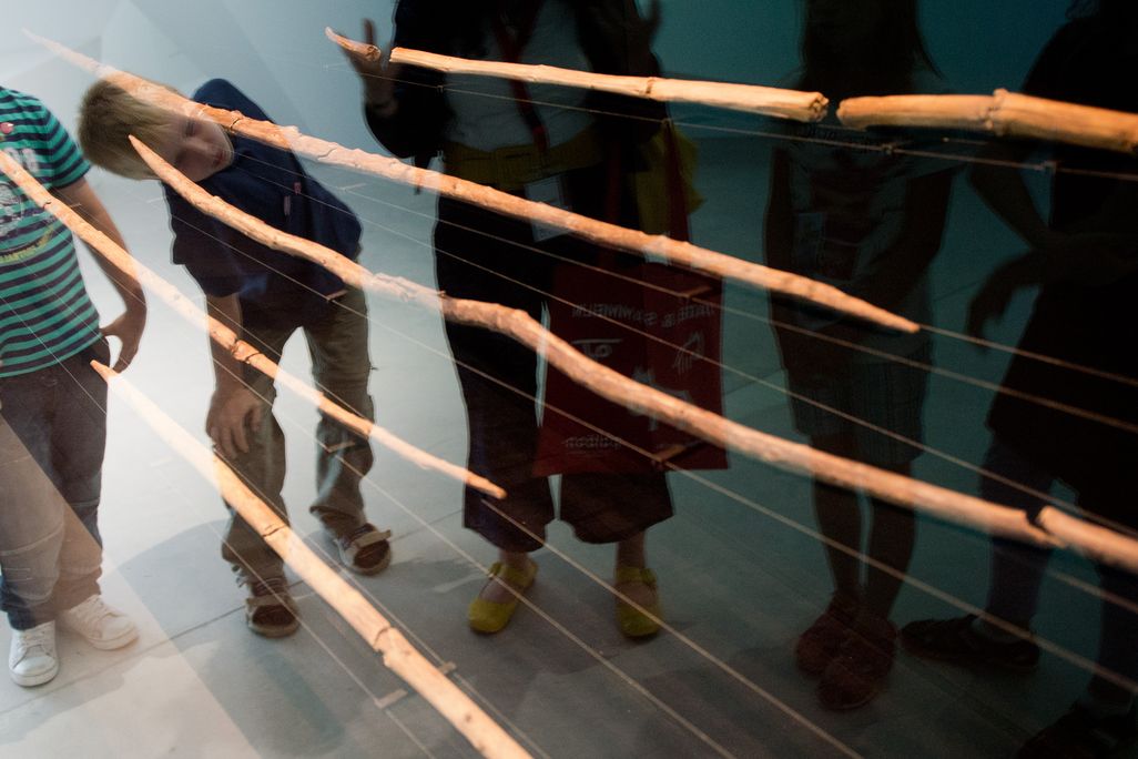 Spears behind glass exhibition pane with kids looking at them