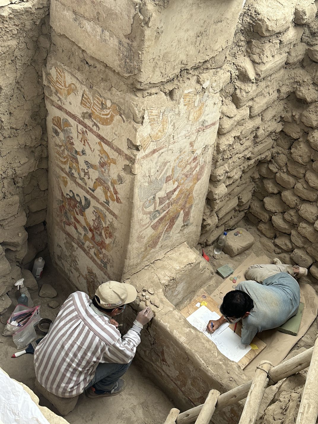 Conservator César Alfredo Velásquez and archaeologist-painter Pedro Neciosup work on the painted throne.