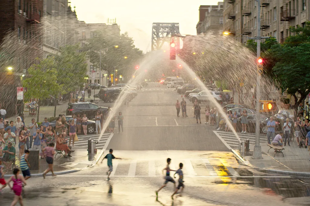 Children run through sprinklers in Washington Heights