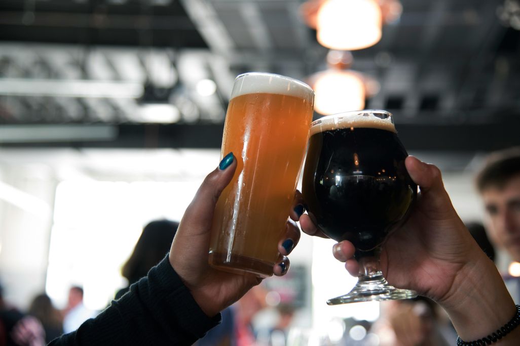 Two people cheersing two glasses of beer