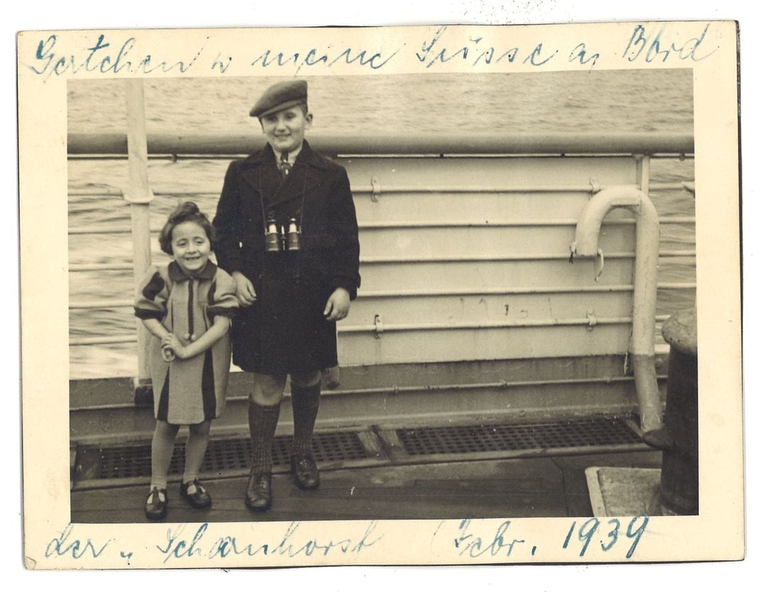 A yellowed image of a small girl and an older boy, smiling on the deck of a ship; dated 1939