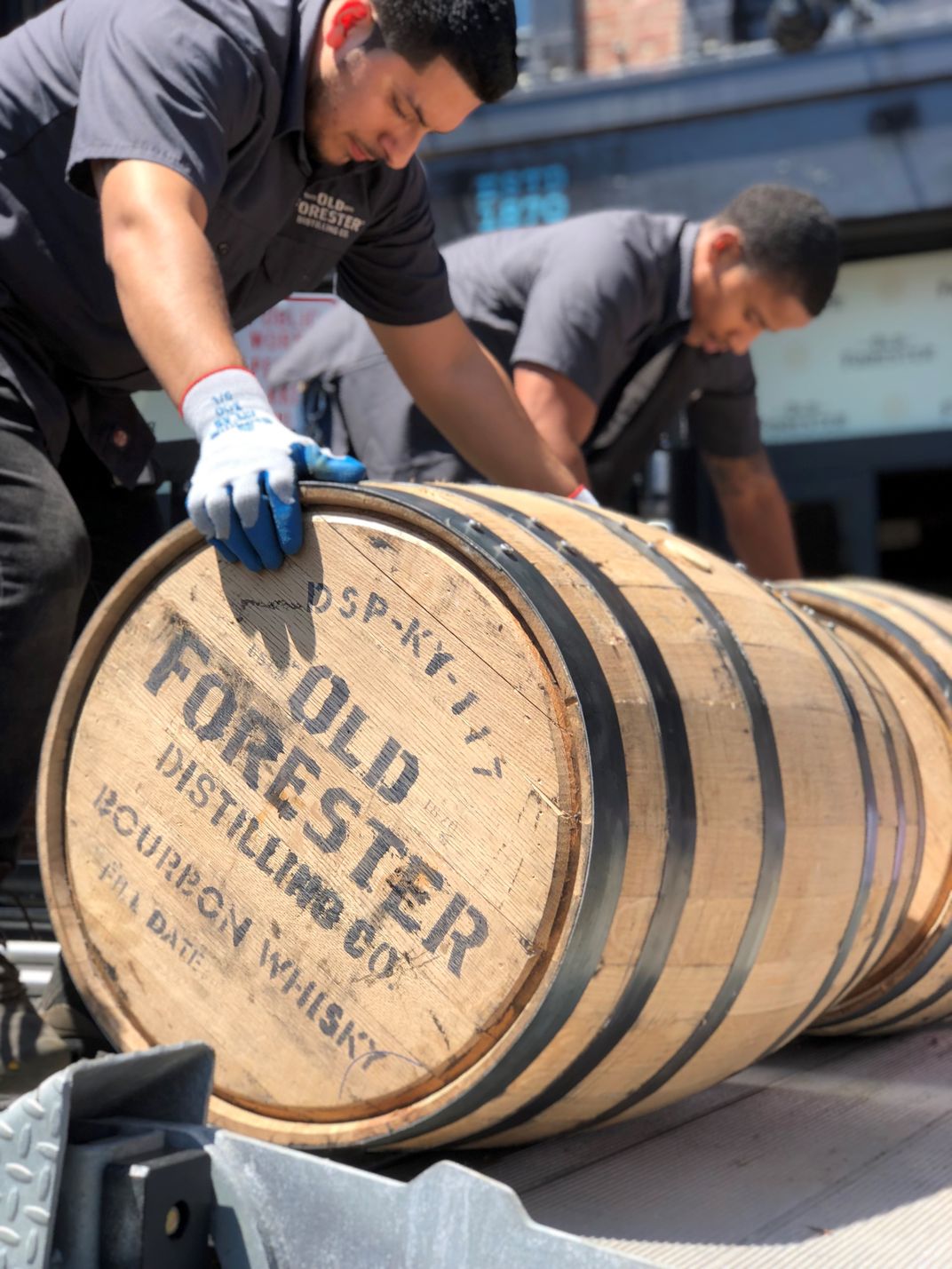 Two men rolling a barrel that says Old Forester