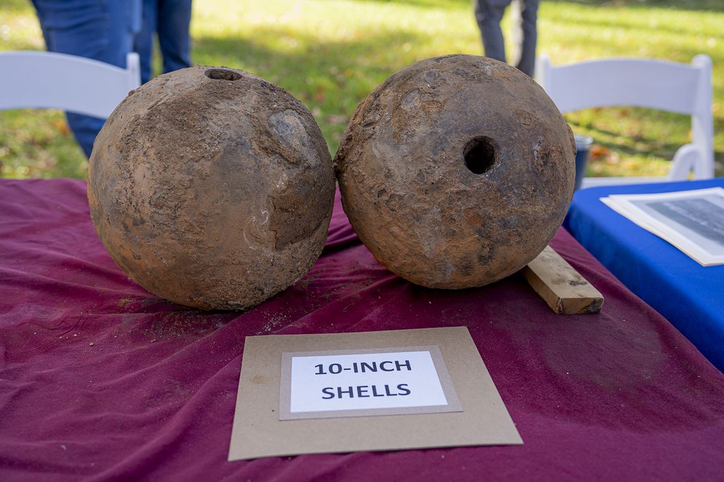Two artillery shells sitting on a table next to a sign that reads 10-inch shells