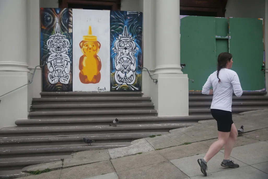 A jogger runs past a large honey bear by street artist fnnch in San Francisco