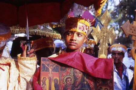 A huddle grows around the high priests, with one young priest bearing an ikon, or holy picture, while others hold ornate gold and silver crosses. 
