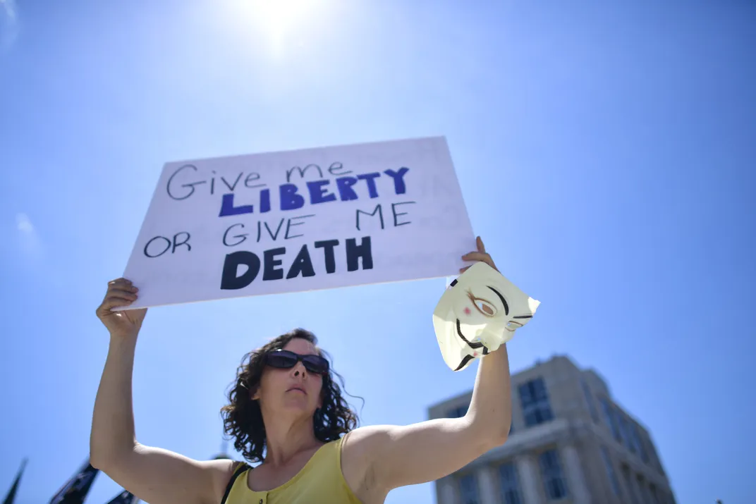 A woman holds a poster featuring Henry's famous phrase at a Pennsylvania demonstration protesting the continued closure of businesses due to the Covid-19 pandemic in May 2020.